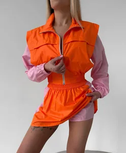 Two-piece women's sporty set with orange and pink color block zip-up top and skirt.