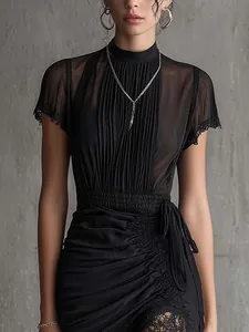 Close-up detail of black sheer mesh dress featuring pleated texture and elegant lace trim