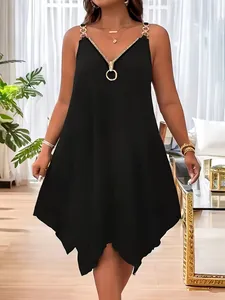 Detalle de vestido negro con cuello en V, cremallera única y tirantes de cadena dorada.