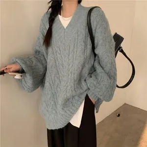 Dettaglio di un maglione blu a trecce con scollo a V e trama di maglia spessa e morbida