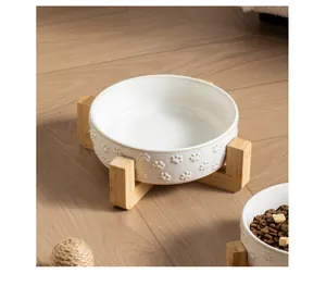 Detailed view of white ceramic cat bowl with embossed paw prints and sturdy bamboo stand