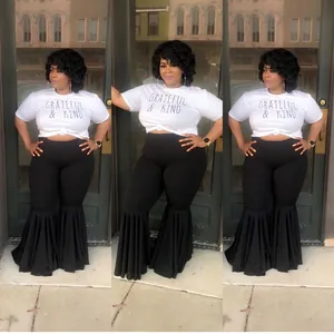 Detail of black high-waisted flare trousers with dramatic pleated ruffle hem and white tee