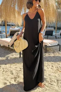 Close-up of a elegant black loose-fit spaghetti strap maxi dress on a sunny beach