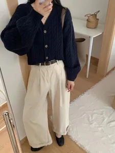Detail view of navy blue cable-knit cardigan paired with beige wide-leg trousers