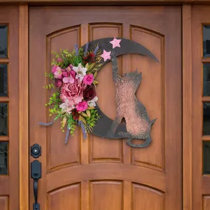 Primo piano della ghirlanda a mezzaluna con fiori rosa e sagoma di gatto su una porta.