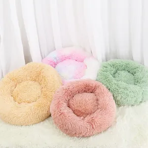 Selezione di letti rotondi in peluche per gatti e cani in vari colori su tappeto bianco