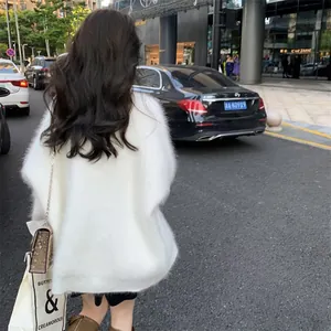 Back view of woman wearing a white fuzzy shaggy oversized cardigan sweater in a city street