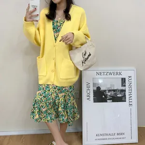 Oversized yellow V-neck knit cardigan with pockets styled over a green floral dress