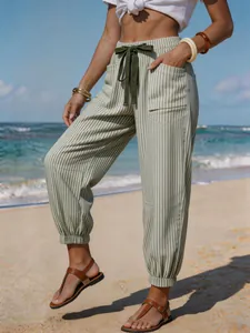 Detailed view of striped linen-look drawstring jogger pants in a sunny beach setting