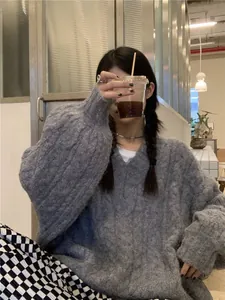 Dettaglio della spessa trama a trecce su un maglione grigio oversize con scollo a V