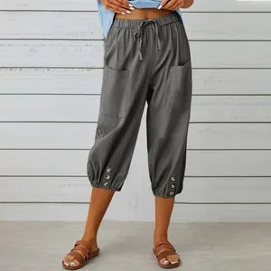 Close-up of casual grey cropped pants featuring a drawstring waist and button hem details