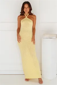 Full-length view of a light yellow halter-neck knitted maxi dress with diamond crochet pattern