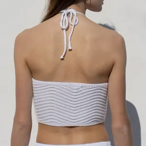 Close-up of white knitted halter neck crop top showing backless design and texture