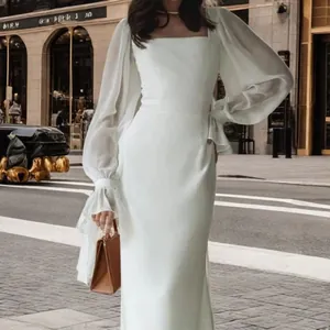 Close-up of an elegant long-sleeve mermaid wedding dress with a chic square neckline outdoors.