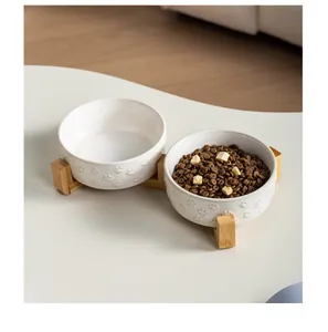 Detailed view of white ceramic pet bowls with paw patterns on a bamboo stand
