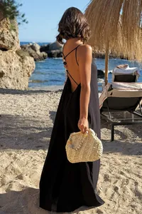 Back view of a black sleeveless backless maxi vacation dress on a sunny beach