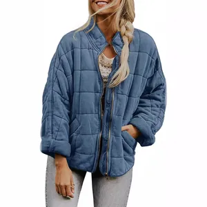 Detail of women's oversized blue quilted jacket featuring a stand collar and zip
