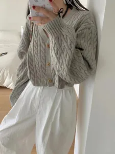 Close-up of thick grey cable knit cardigan with button front in a bedroom setting