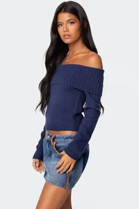 Close-up side view detail of a woman wearing a navy blue off-the-shoulder knit sweater