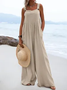 Vista de cuerpo entero de un mono beige sin mangas de lino en una playa de verano.
