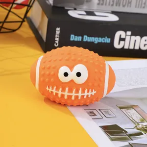 Close-up of orange latex rugby dog toy with cartoon face and textured bumps