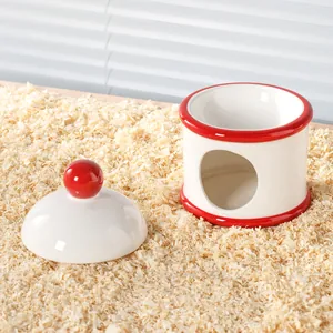 Cachette pour hamster en céramique blanche et rouge posée sur des copeaux de bois