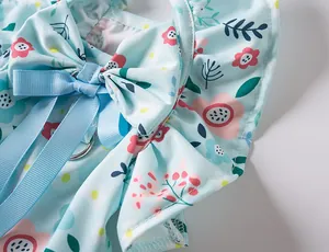 Detailed close-up of a floral pet dress featuring a blue ribbon bow and ruffles.