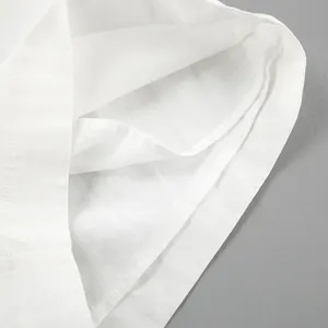 Macro detail shot of white cotton linen fabric showing stitching quality and texture.