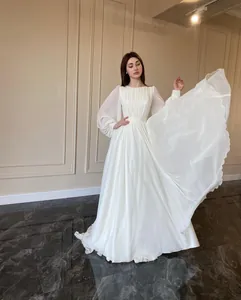 Elegant long-sleeved white wedding dress with lantern sleeves and pleated bodice detail.