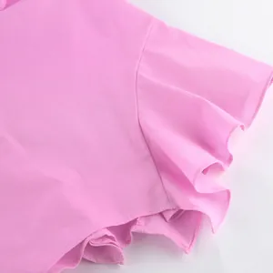 Détail rapproché du bord à volants en coton rose sur un ensemble de vacances chic