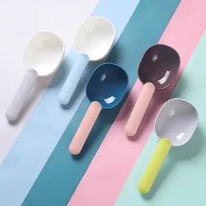 Cinco cucharas de plástico coloridas para comida de mascotas sobre fondo de bloques de colores