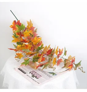 Detailed view of artificial maple leaf garland with autumn berries for Thanksgiving decor.