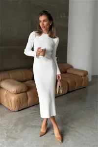 Elegant white long-sleeved ribbed knit maxi dress shown on a model in a lifestyle setting.