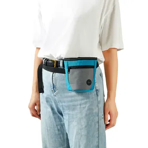Person trägt eine blau-graue magnetische Futtertasche für das Hundetraining am Gürtel