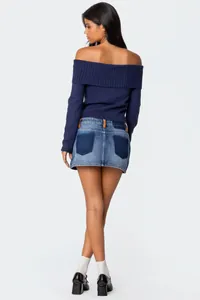 Detailed back view of a woman in a navy off-the-shoulder knit sweater and denim skirt.