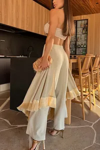 Detail view of elegant beige wide-leg trousers with stylish fringe hem decoration.