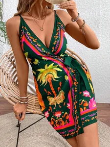 Detailed view of the tropical palm and butterfly print on a green V-neck strap dress.