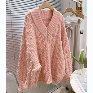 Dettaglio della trama del maglione rosa con scollo a V e trecce in stile oversize