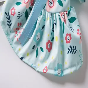 Macro view of light blue floral pet dress fabric with ruffled hem and blue ribbon.