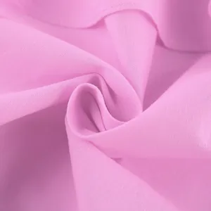 Gros plan sur un tissu en coton rose montrant des volants doux et une maille fine.