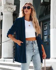 Detailed macro view of a navy blue velvet long-sleeve coat styled with denim jeans and gold jewelry