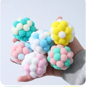 Close-up macro detail of colorful macaron plush cat balls held in hand for play.