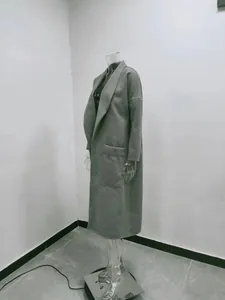 Detailseitenansicht eines minimalistischen grauen Wollmantels auf einer Schaufensterpuppe.