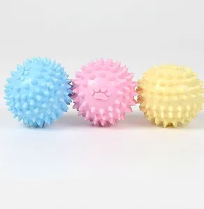 Dettaglio delle palline spinose in TPR blu, rosa e gialle per cani con impronte di zampa.