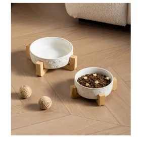 Detailed view of white ceramic pet bowls with paw patterns on bamboo stands.