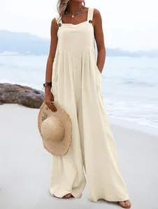 Mono informal beige sin mangas de pierna ancha con botones en un entorno de playa.
