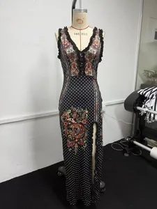 Détail d'une robe longue sans manches à pois avec imprimé paisley et fente haute.