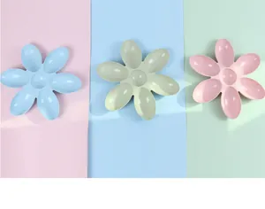 Zicht op drie bloemblad-vormige kattenbakken in pastel roze, blauw en groen plastic