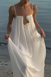 Close-up of white pleated resort maxi dress featuring a unique U-shaped wire neckline detail