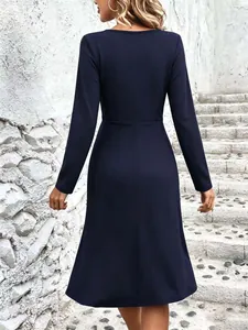 Back view of a navy blue long-sleeved midi dress with a flared A-line skirt and waist seam.
